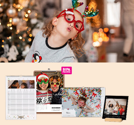 Kind mit Rentierbrille vor dem Weihnachtsbaum, unten BIPA Fotoshop Fotokalender mit festlichen Bildern und persönlichen Motiven.