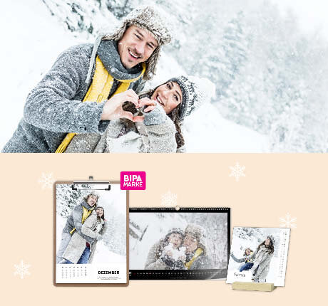 Paar im Schnee zeigt Herz mit Händen, darunter personalisierte Fotokalender mit winterlichen Bildern für 2024.